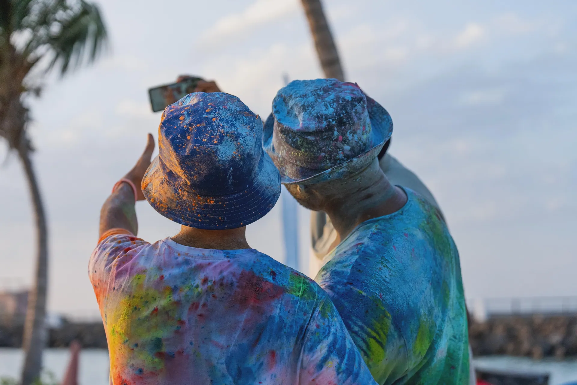 Two friends covered head to toe in colour powder taking a phone selfie