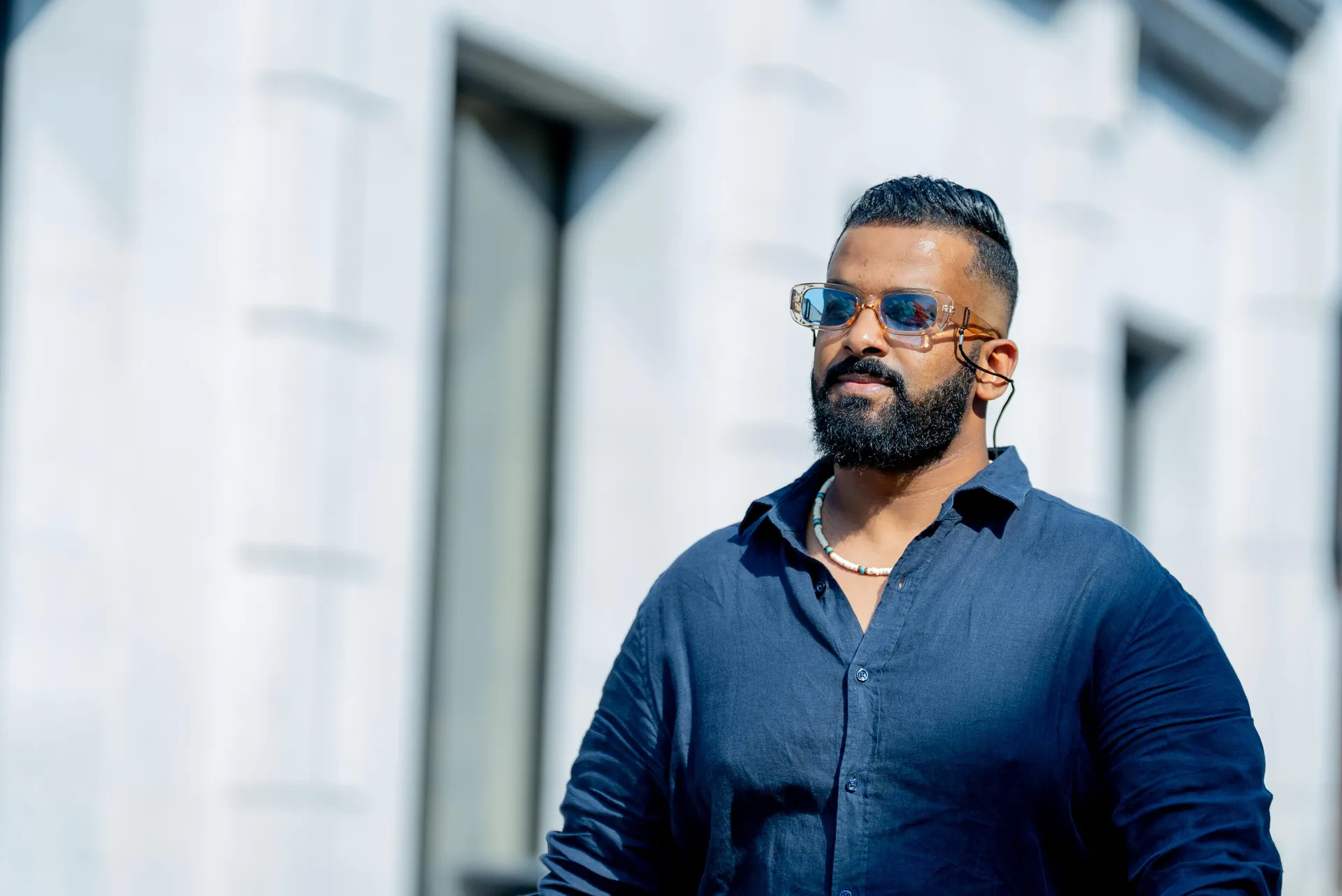 Man in a navy shirt and tinted glasses against white carved stone