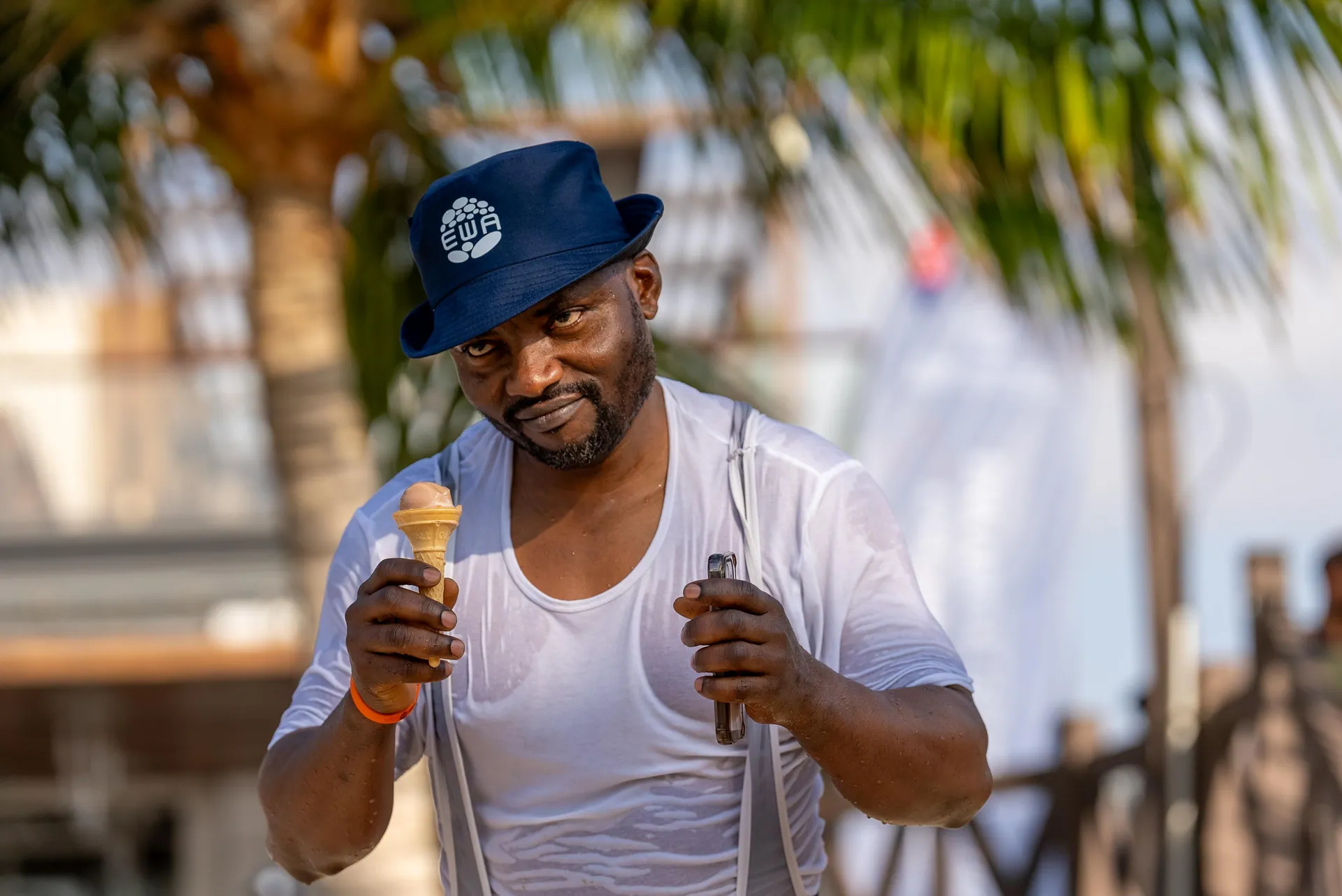 Man in an EWA bucket hat holding an ice-cream cone at the beach