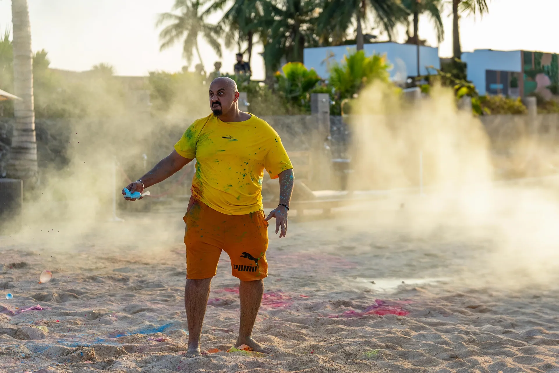 Colour powder cloud drifting across a beach court at golden hour