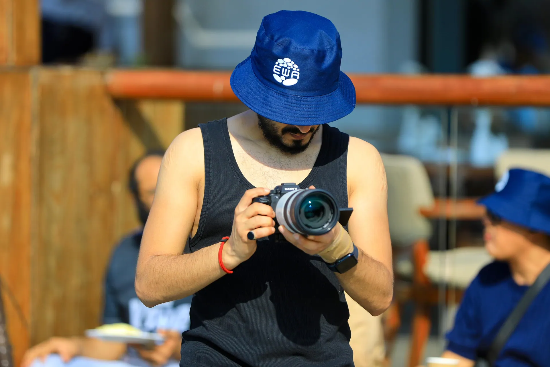 The photographer in a blue bucket hat checking a frame on his camera