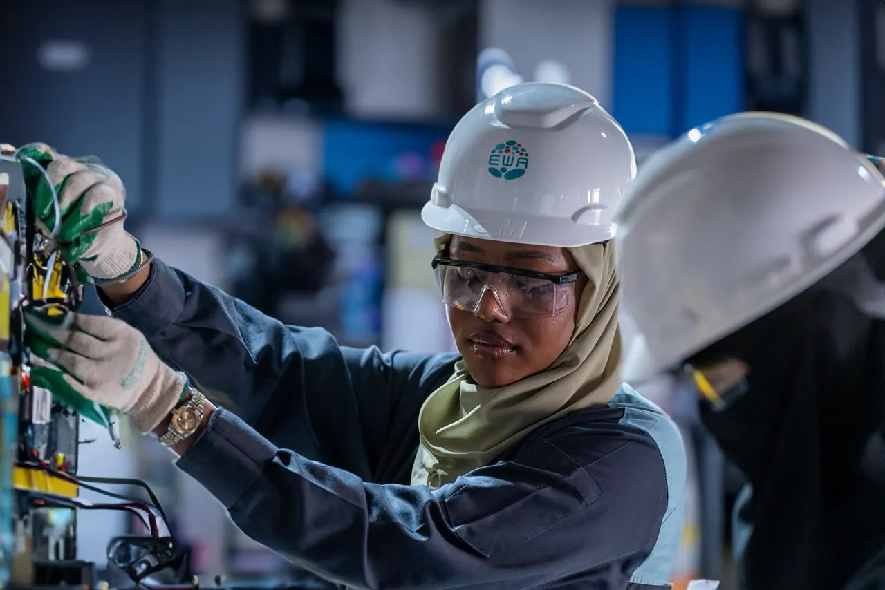 Two engineers in hard hats wiring a training panel