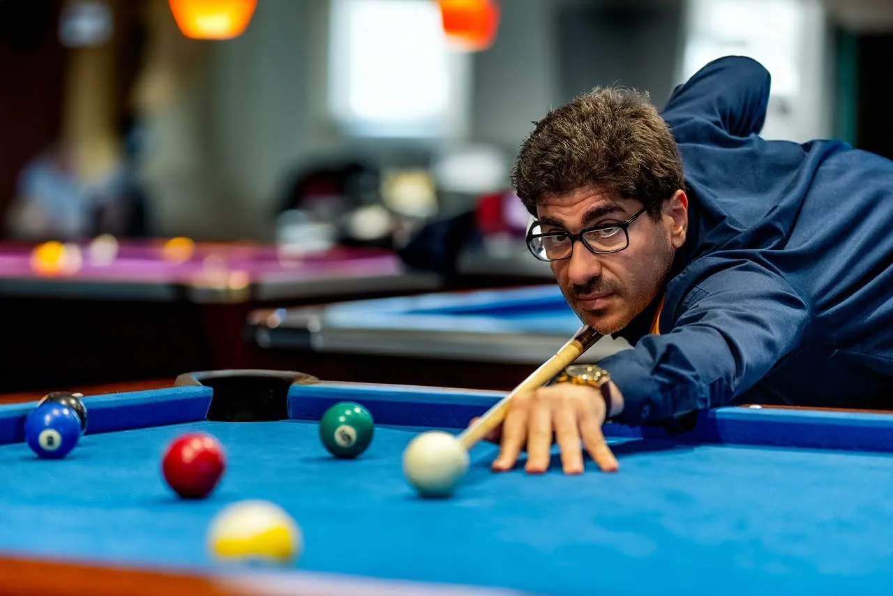 Man lining up a shot across a blue billiards table