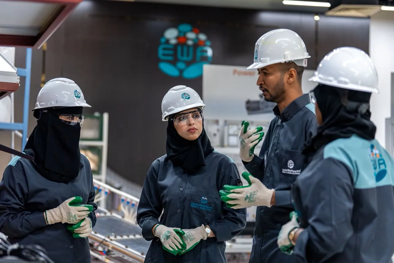 Team in hard hats talking beneath the EWA logo